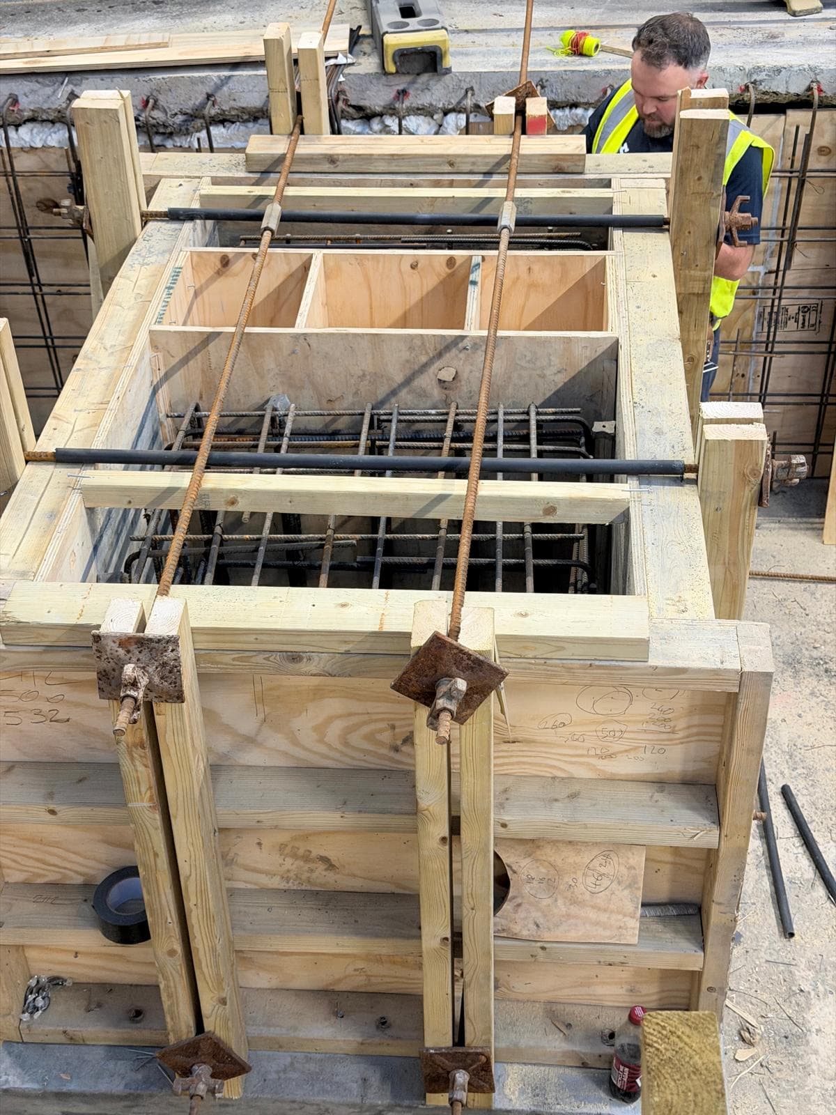 Deep rebar trench foundation with yellow safety caps at the Bow basement project