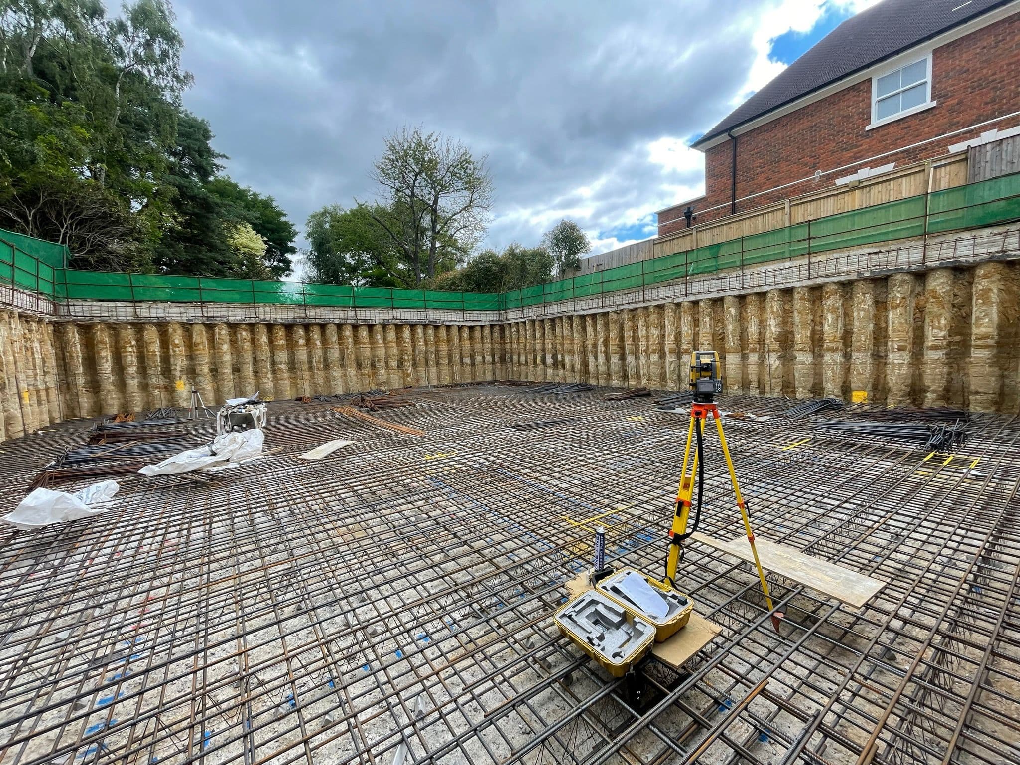 Excavated basement footprint at Virginia Water with full rebar grid and survey theodolite